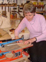 Sue Kane in the workshop cutting silver sheet.